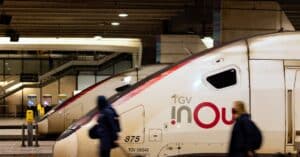 Travelers pass by TGV trains at a bustling Paris railway station, capturing the essence of urban transit.